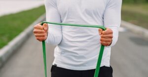 Man in sportswear using resistance band for outdoor fitness routine.
