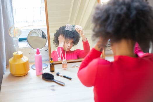 African American woman combing hair in front of a mirror indoors.