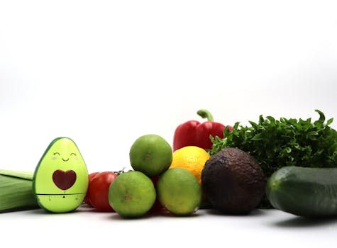 An array of fresh vegetables and fruits alongside a smiling avocado kitchen timer.