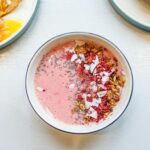 Delicious pink smoothie bowl with granola, chia seeds, and coconut flakes for a healthy breakfast.