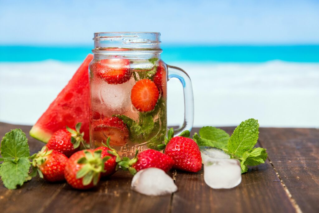 Chilled drink with strawberries, watermelon, and mint in a mason jar, perfect for summer refreshment.