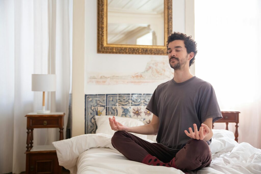Discover tranquility as a man meditates in a serene bedroom environment, capturing the essence of peace.