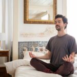 Discover tranquility as a man meditates in a serene bedroom environment, capturing the essence of peace.