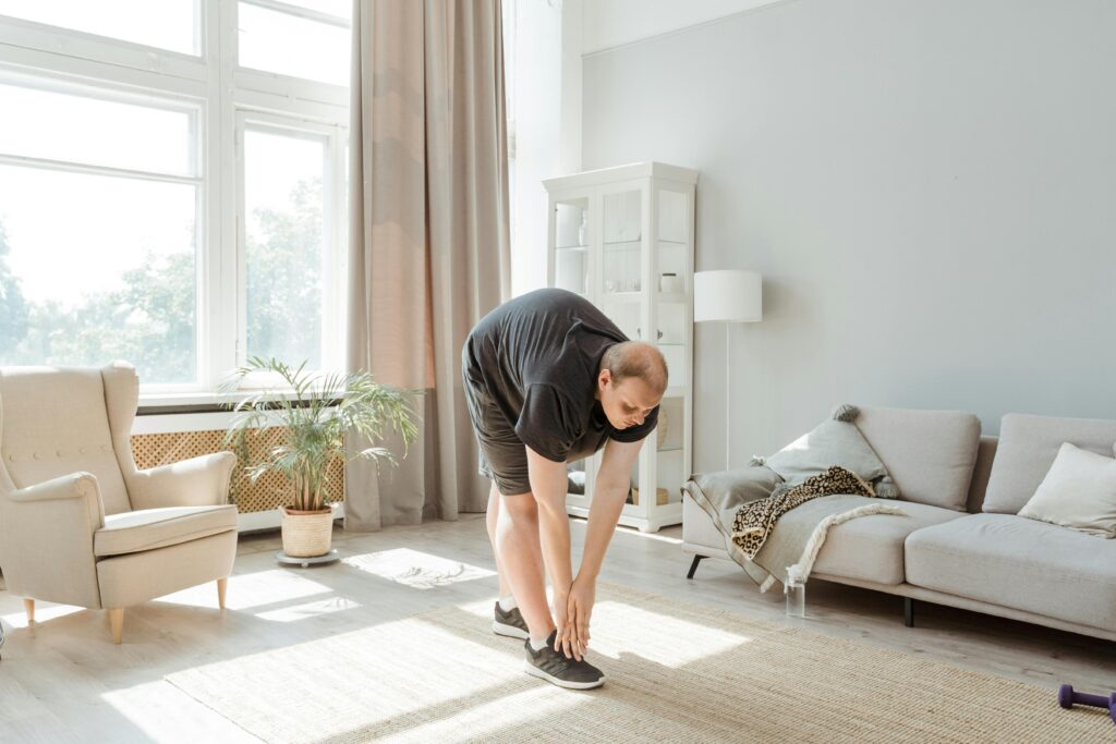 Adult exercising and stretching in a bright living room with natural light.