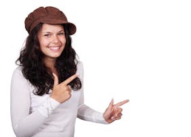 Smiling woman wearing a brown hat pointing against a white background.