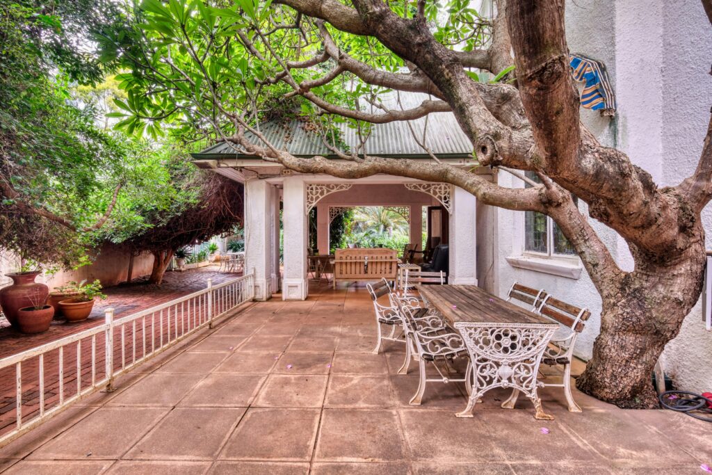 Rustic outdoor patio with vintage furniture and lush greenery, perfect for relaxation.