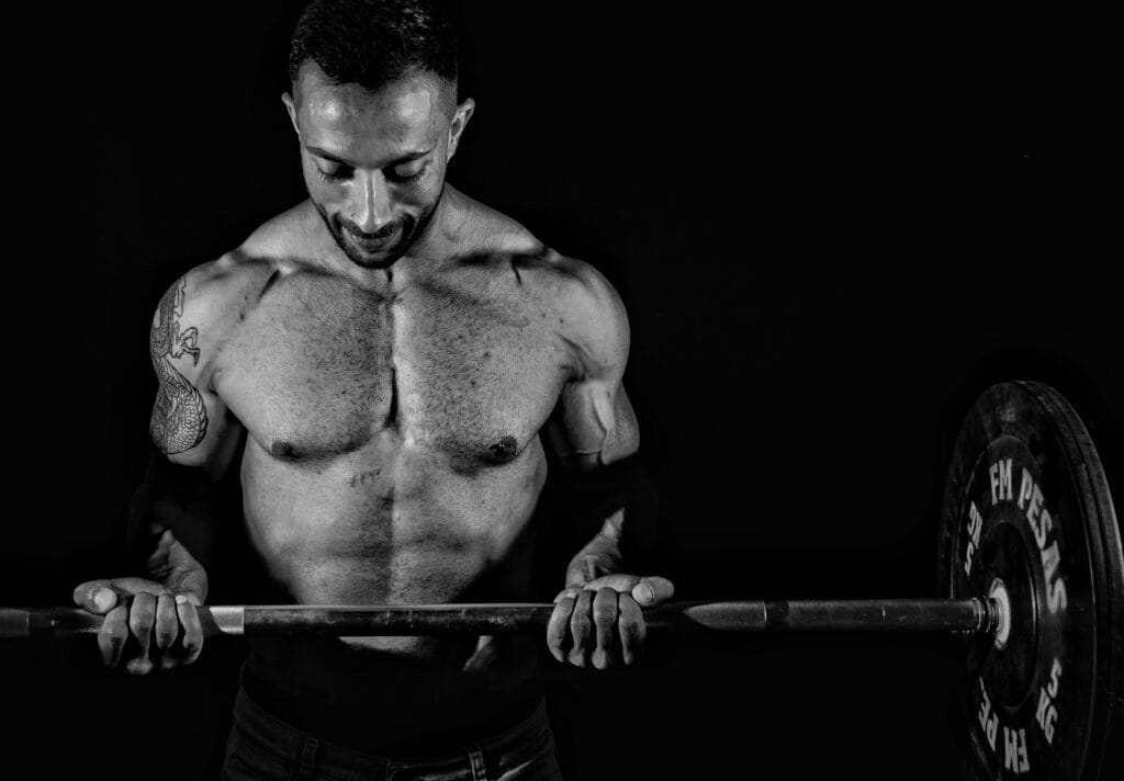 Dramatic black and white photo of a muscular man lifting weights, focusing on strength.