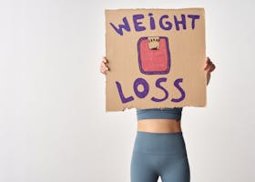 Person holding 'weight loss' sign for fitness motivation and health goals.