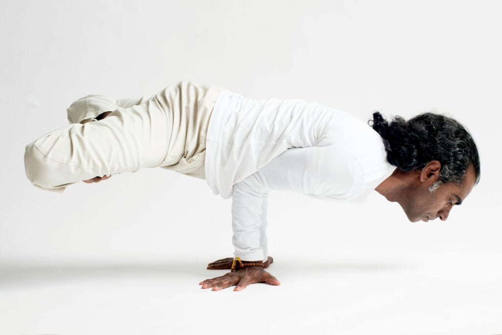 Man performing a balanced yoga pose in a studio setting, showcasing strength and mindfulness.