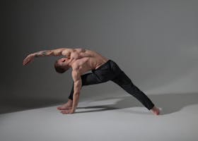 A male performing a side plank yoga pose, showcasing balance and strength in the studio.