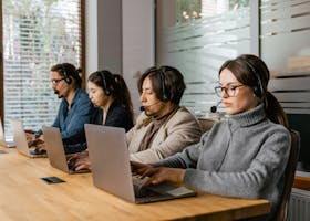 A diverse call center team uses laptops and headsets to provide customer support efficiently.