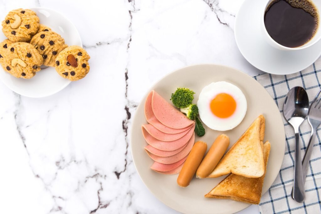An appetizing breakfast spread featuring eggs, sausages, toast, and coffee on a marble surface.